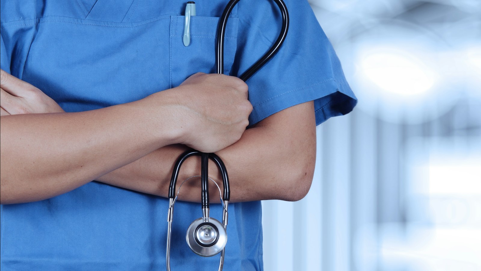 A person in scrubs with a stethoscope on their arm