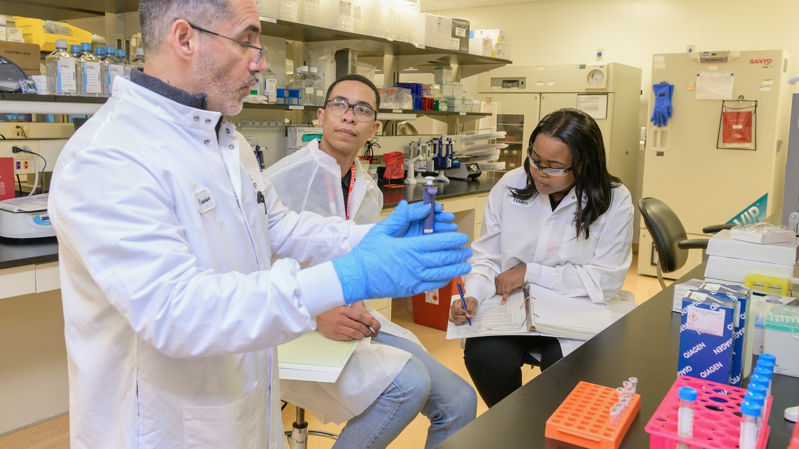 Three scientists in a laboratory discussing a sample