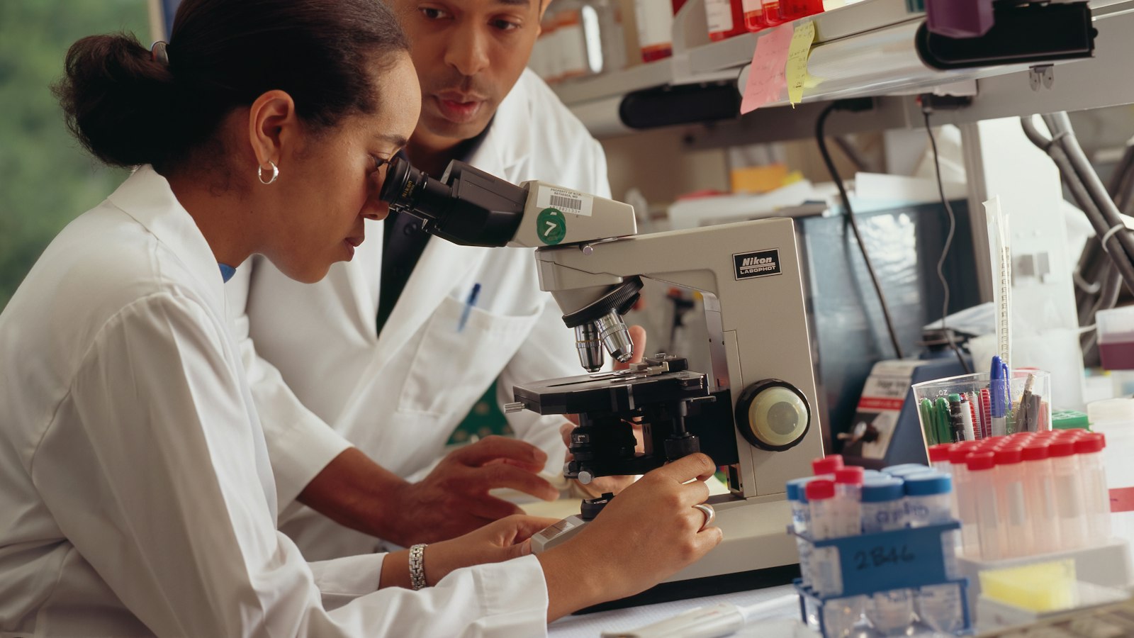 Two scientists at a microscope in a laboratory