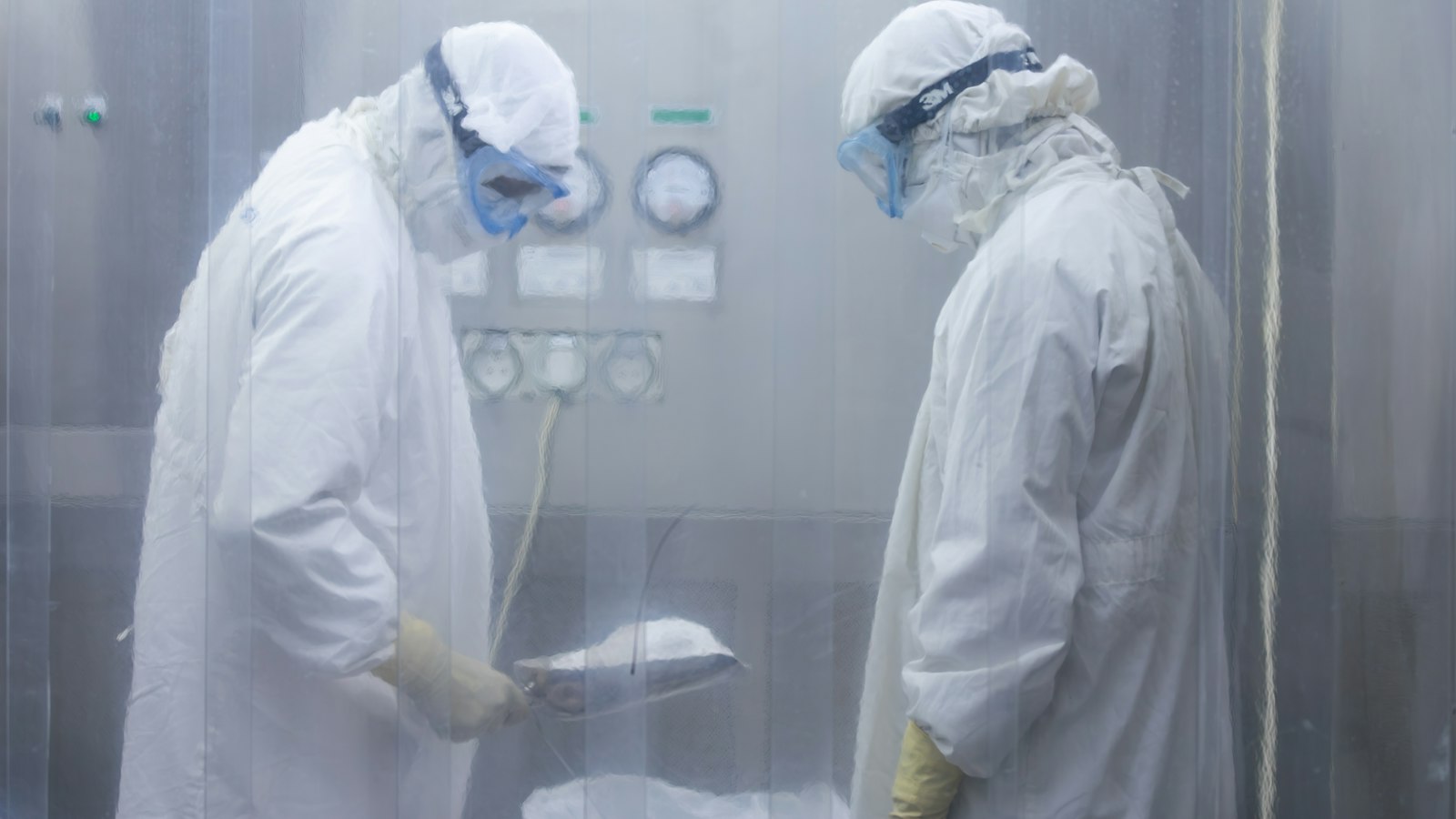 Two scientists in protective suits working in a cleanroom